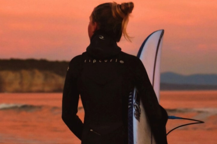 a person with long hair and a sunset in the background